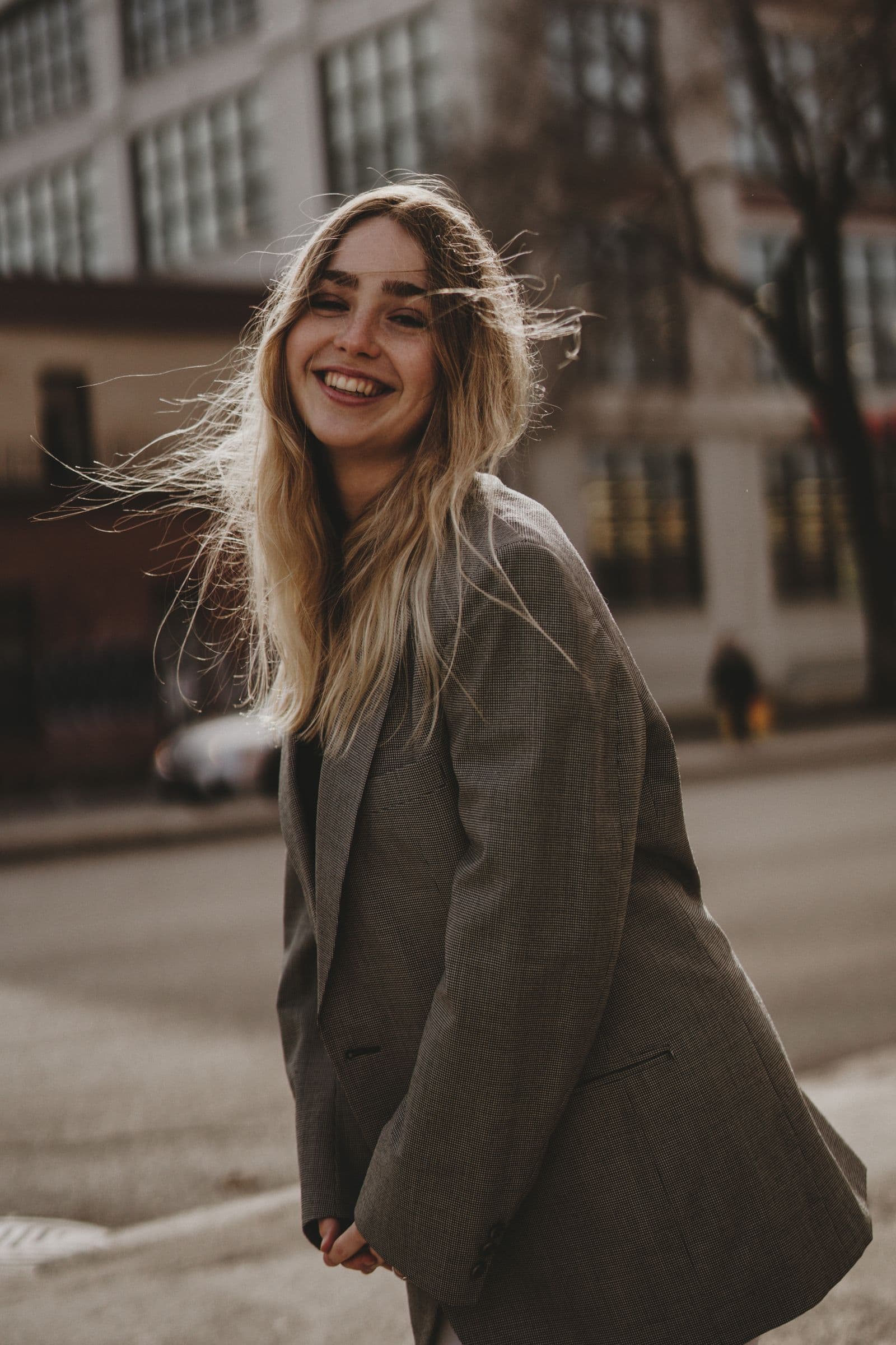 A woman laughing as she turns, on a city street in winter light.