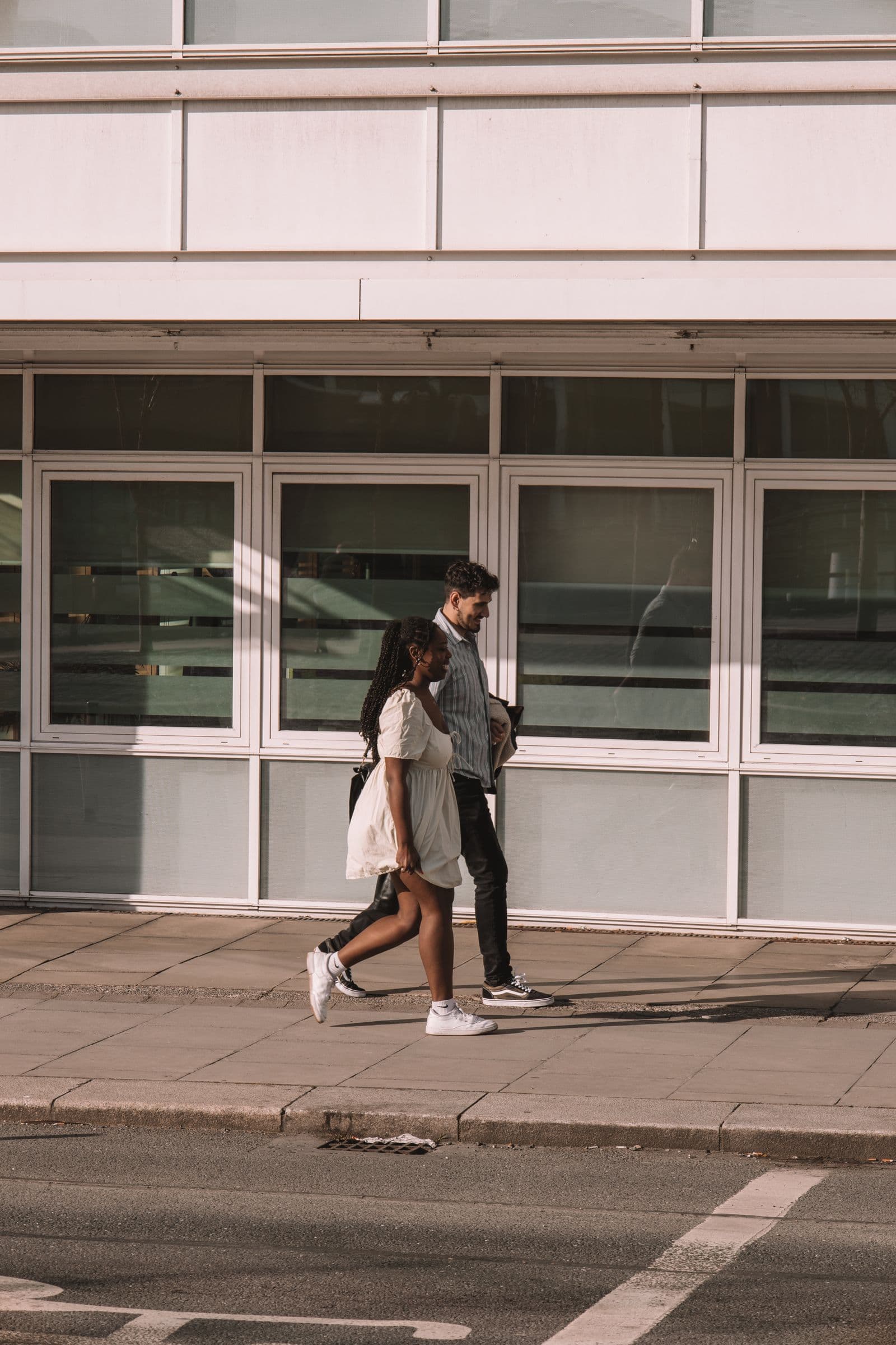 Two people walking along a city street in the late afternoon.